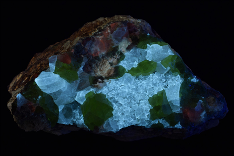 Unlike the sulfur above, this sample is lit under long-wave UV light, not short-wave. But it still appears green, because it’s interfering with the fluorescent mineral beneath it.